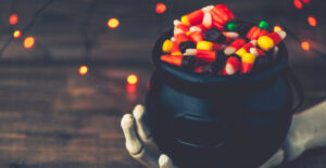 Halloween-Hintergrund mit Kesselbonbons und Skeletthand