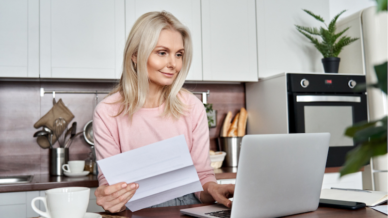 Ältere Dame auf Jobsuche vor dem Laptop.