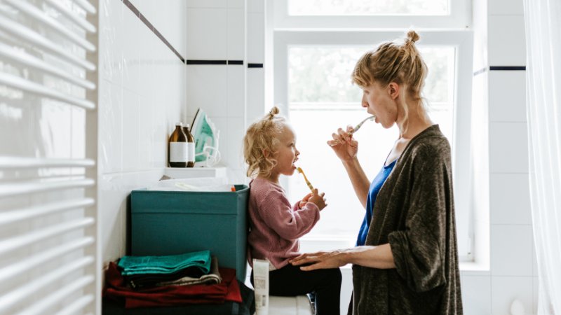 Mutter und Tochter putzen gemeinsam im Bad ihre Zähne