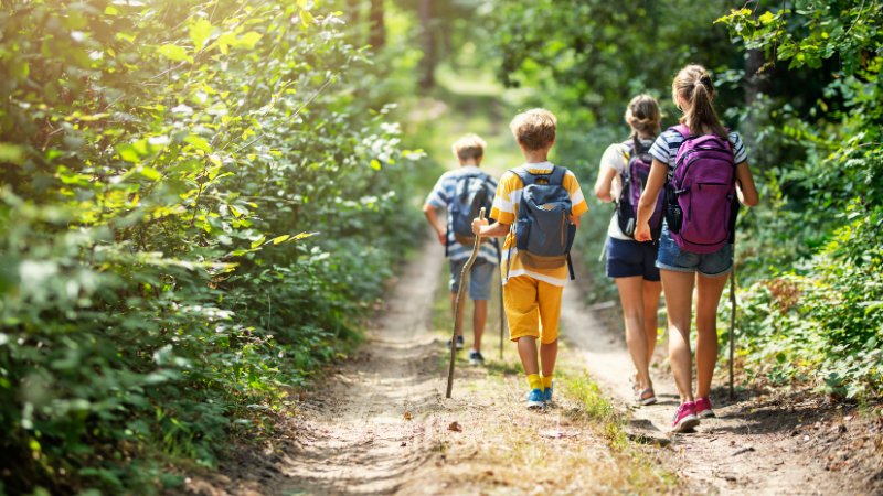 Eine Mutter genießt eine Wanderung mit ihren drei Kindern.