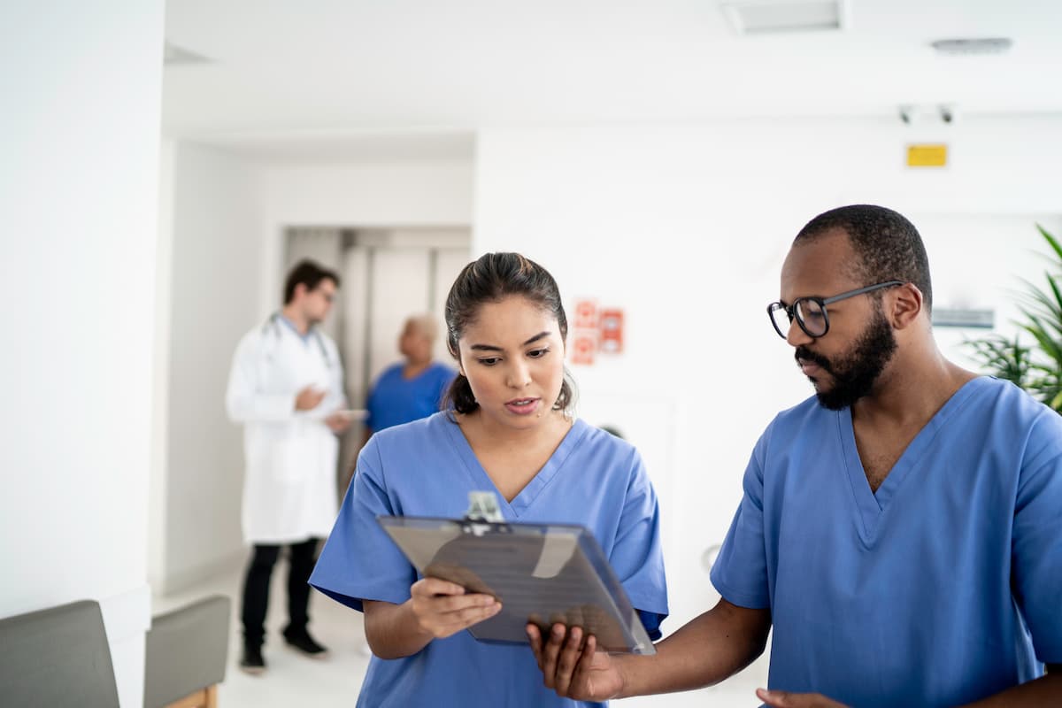 Zwei Krankenpfleger schauen gemeinsam auf ein Klemmbrett