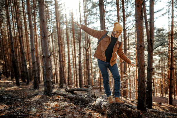 Visualisierung Rebalancing: Junger Mann balanciert auf einem Stamm im Wald